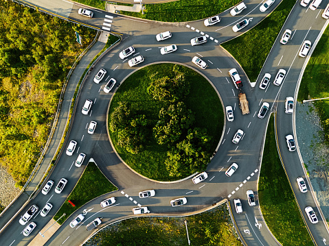 Aerial view of white cars on a roundabout at rush hour. Composite image.