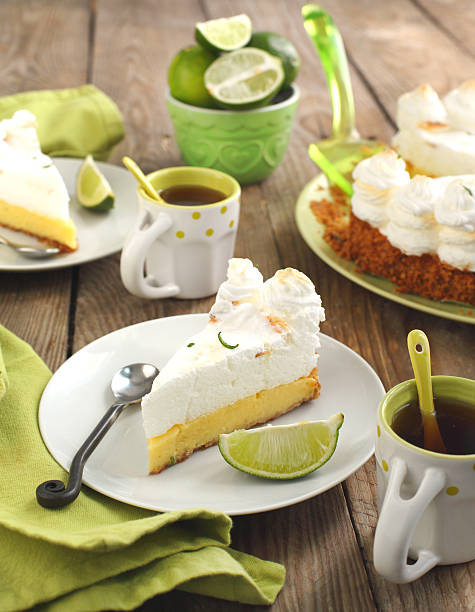 slice of key lime pie mit frischen limetten - key lime pie dessert pie pastry stock-fotos und bilder