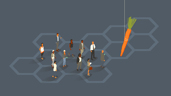 A group of 11 people are dressed for business, illustrating the concept of external motivation as they follow an oversized carrot dangling from a string, presumably from a stick not seen within the boundaries of the image. Diverse men and women use digital devices. Isometric vector presented in a 16x9 artboard, over a slate gray background and a hexagonal honeycomb pattern.