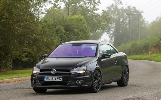 Whittlebury,Northants,UK -Aug 26th 2023: 2013 black diesel engine Volkswagen EOS car travelling on an English country road on a damp and misty morning.