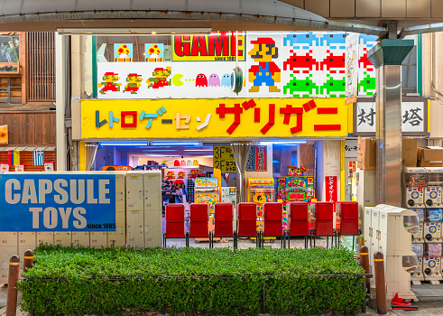 osaka, japan - dec 04 2022: Retro Game Center Zarigani located in Tsutenkaku Hondori Shopping Street featuring capsule toys machines and iconic games like Super Mario Bros, Pac-Man or Space Invaders.