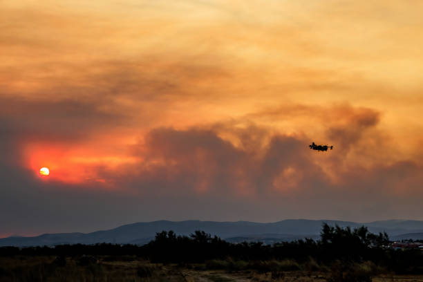 Devastating wildfire in Alexandroupolis Evros Greece, Aerial firefighting waterbombing planes silhouette, smoke covered the sky, sunset colors.