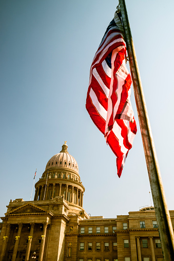 Unique view of the State capitol building of the state of Idaho in Boise Idaho, USA with USA flag in the front. Picture was taken on a fine summer morning