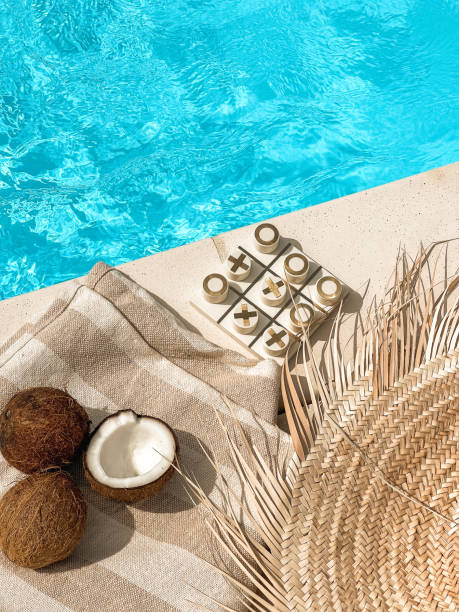 istock Tropical swimming pool with straw hat, coconuts and board game poolside from above 1640818817