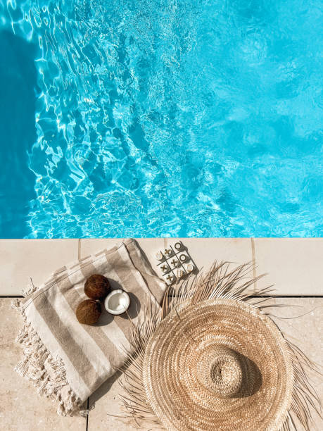 istock Tropical swimming pool with straw hat, coconuts and board game poolside from above 1640825003
