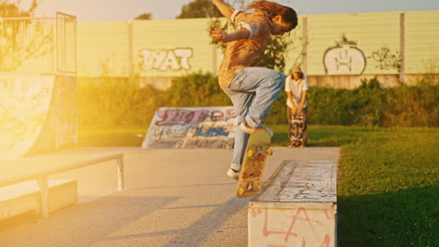 Cool Skateboarder Doing Tricks Jumping and Sliding on Bench in Skate Park at Sunset