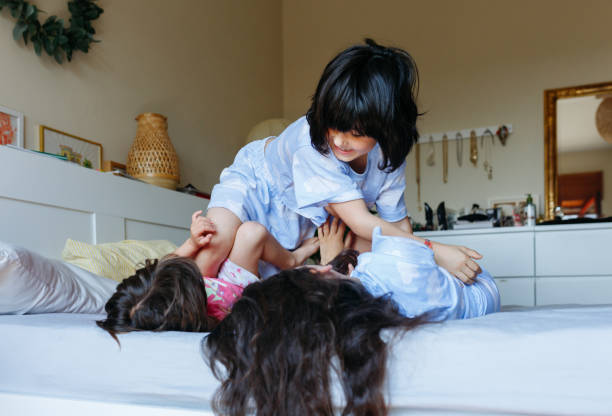 istock two children lying on the bed and other child jumping over 1640852347