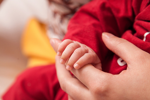 Detail of mother and daughter holding hands. Fingers detail. Care concept. Affection concept.