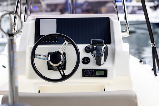 Luxurious boat control cabin with white leather seats, steering wheel, gear lever and on-board computer.