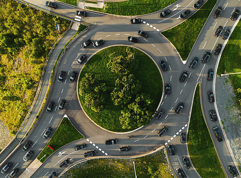 Aerial view of black cars on a roundabout at rush hour. Composite image.