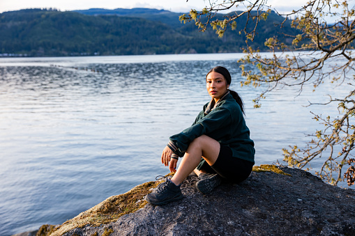 A hispanic woman stands in the Columbia River Gorge Scenic area of Oregon, at Sunset. Shot in Oregon, Pacific Northwest.