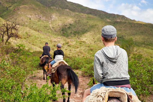 Family riding on horseback through the hills. Grandfather and grandsons on holidays