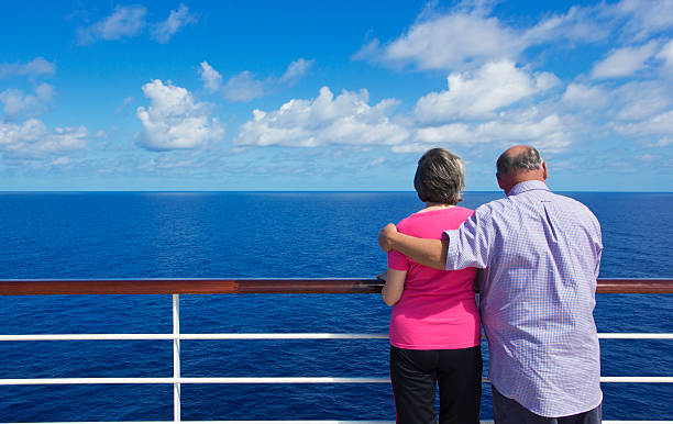 Senior Couple on a ocean cruise A senior couple looking out at the ocean while on deck a cruise ship cruise ship people stock pictures, royalty-free photos & images