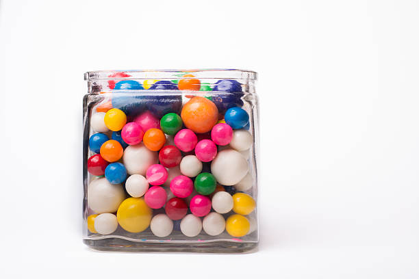 A square glass jar full of colorful bubble gum balls.