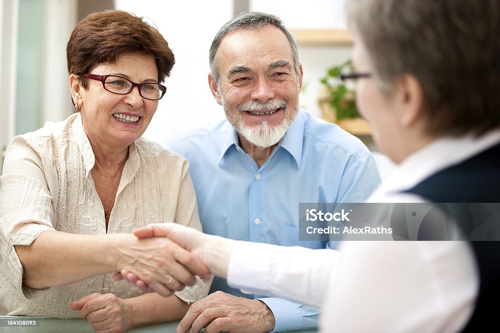 An old couple shaking hands with an unseen woman Smiling senior couple shaking hands with a consultant Financial Advisor Stock Photo