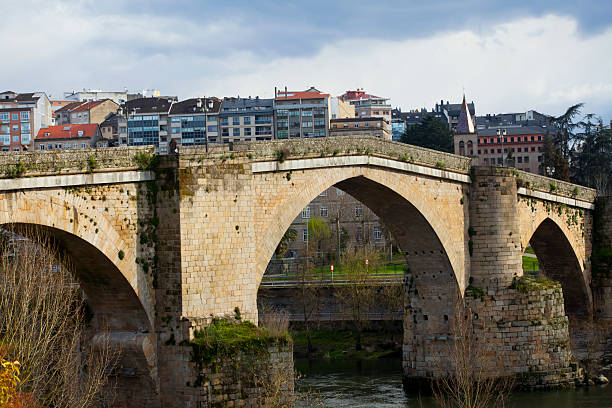 Roman bridge in Ourense (Galicia, Spain), over river Miño and city scape in the background..