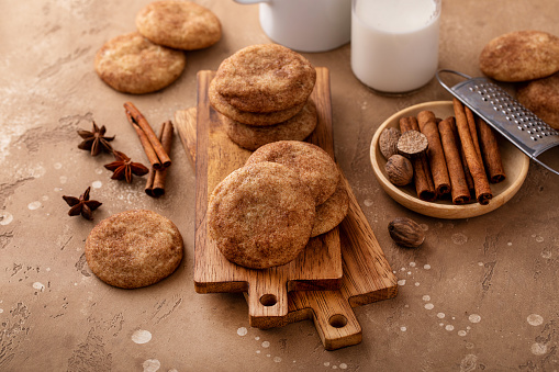Cinnamon cookies tossed with cinnamon sugar on wooden board with milk, classic snickerdoodle cookies