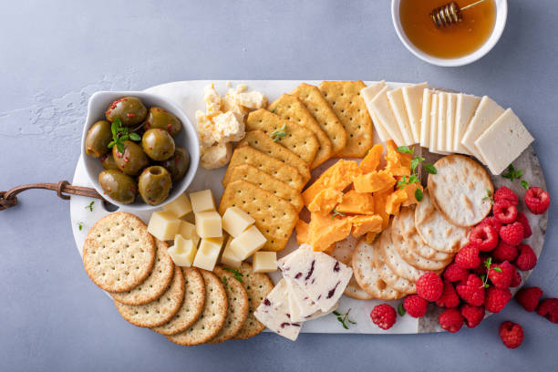Cheese board or snack board with crackers, cheese, olives and berries