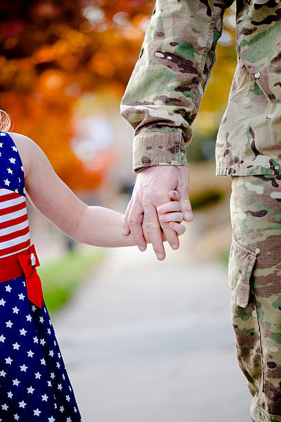 Soldier holding daughter's hand stock photo