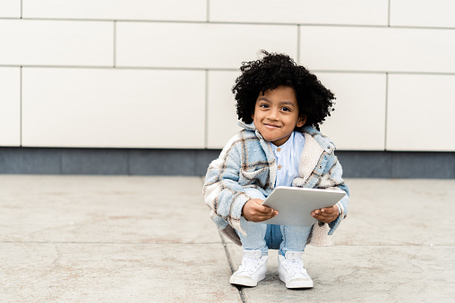 Portrait of a cute African American little boy using a digital tablet outdoors
