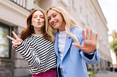 Medium shot portrait of lovable caucasian young women expressing positive emotions looking at camera. Outdoor photo of cheerful girlfriends posing on city.