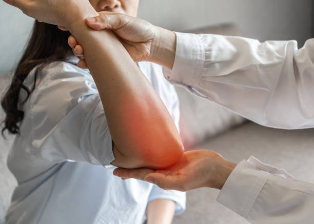 整形外科または理学療法士クリニックで理学療法の相談を受けている女性患者のリウマチ、肘の痛み、痛み、けいれん、しびれ、関節リウマチ、変形性関節症 - pain elbow physical therapy inflammation ストックフォトと画像