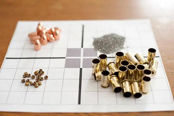 Bullets, primers, cases and powder all sitting on a target on a wooden table. This photo could be used for so many themes.