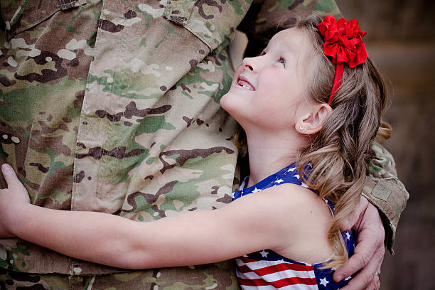 Soldier's Daughter Soldier's daughter hugging and looking up at her father. military deployment photos stock pictures, royalty-free photos & images