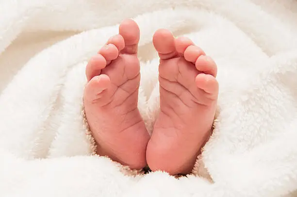 Babyfeet on white coverlet. Toes. Horizontal photo. Macro. Close-up.