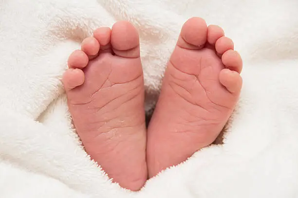 Two babyfeet on white coverlet. Toes. Horizontal photo. Macro. Close-up.