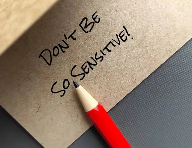 Red pen on handwriting craft paper card Don't Be So Sensitive, a gaslighting message to accuse or emotional abuse others to question their beliefs or doubt their perceptions and become distressed