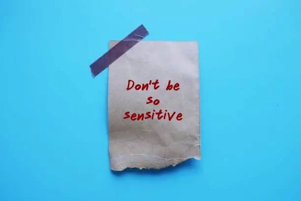 Torn paper stick on blue background with handwriting Don't Be So Sensitive, gaslighting message to accuse or emotional abuse others to question their beliefs or doubt their perceptions and become distressed