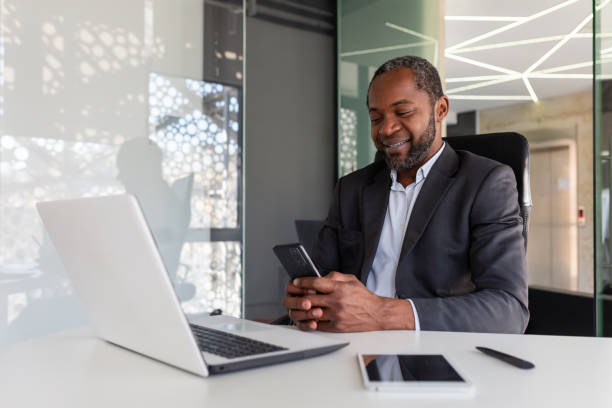 istock Mature experienced and successful african american boss at workplace inside office, senior satisfied with results businessman using phone, reading news from online app on smartphone 1641234856