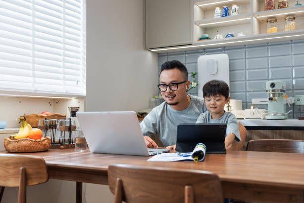 istock Father holding his son and working at home 1641283929