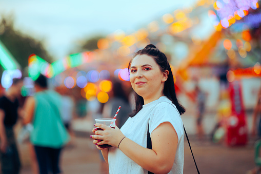 Smiling young woman having a cherry juice at the festival