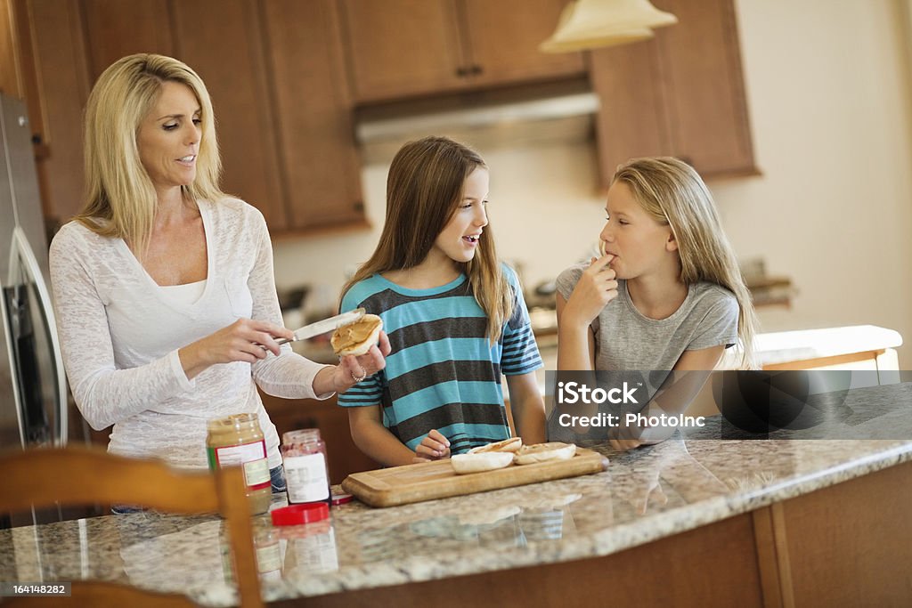 Mature woman applying peanut butter on bread Mature woman applying peanut butter on bread slice while daughters looking at each otherhttp://i449.photobucket.com/albums/qq220/iphotoinc/KidsBanner.jpg 14-15 Years Stock Photo