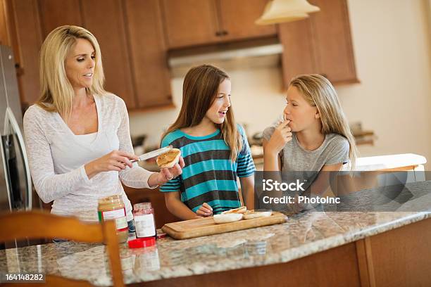 Mature Woman Applying Peanut Butter On Bread Stock Photo - Download Image Now - 14-15 Years, Preparation, Preparing Food