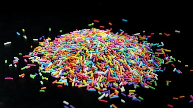 Rainbow color sprinkling sweets in slow motion on a black background