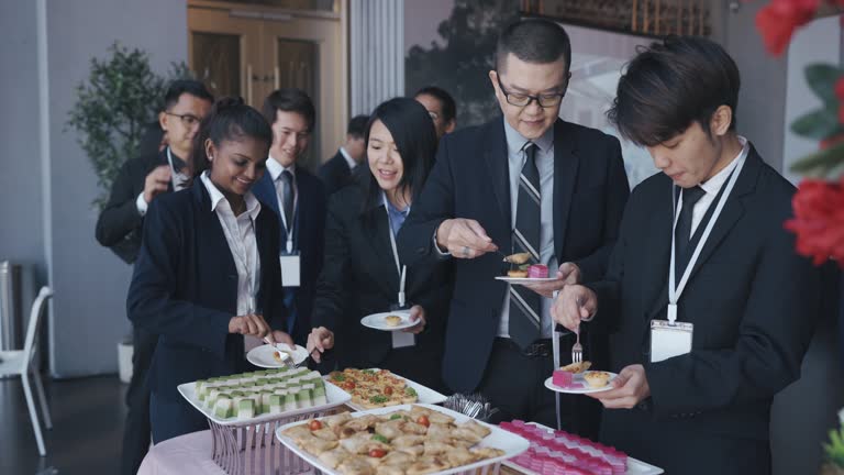 Asian Multiracial Seminar participants picking up food and drink in business conference meeting coffee break