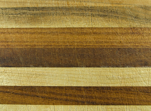 A well used laminated hardwood cutting board with horizontal blocks.