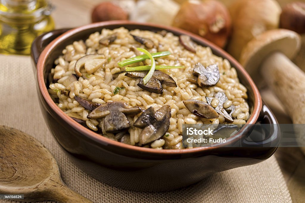 Wild Mushroom Risotto A bowl of rustic wild mushroom risotto against a background of fresh boletus mushrooms. Cooked Stock Photo