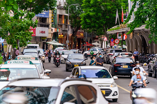 Ho Chi Minh, Viet Nam - 8 July 2023: Colorful perspective of Le Thanh Ton Street with numerous hotel, bar and shop sign boards, crowded with people and motorbikes