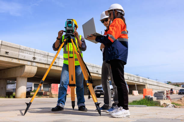 istock Engineer use theodolite equipment and looking blueprints  project on laptop for route surveying to build a bridge across the intersection to reduce traffic congestion during rush hours 1641610743