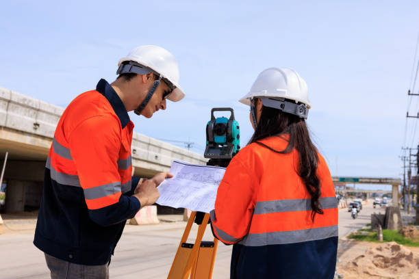 istock Engineer use theodolite equipment and looking blueprints construction project for route surveying to build a bridge across the intersection to reduce traffic congestion during rush hours 1641611204