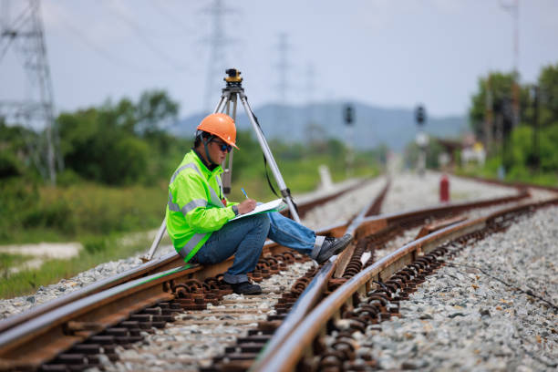 istock Engineer wearing hard hats and uniforms sitting take notes in notebook and theodolite equipment surveying construction worker on Railway site. 1641611828