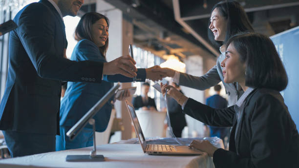 istock Asian Reception checking electronic invitation shown by event participants guest registering at reception desk attending business conference seminar 1641611856