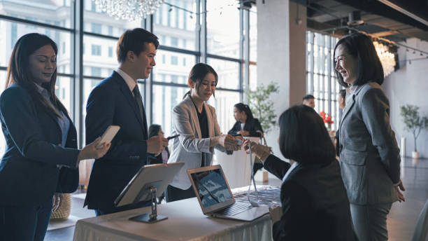 asian event participants guest registering at reception desk attending business conference seminar - self service stockfoto's en -beelden