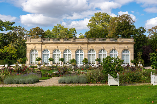 Boulogne-Billancourt, France - August 13 2023: Orangerie in the Bagatelle park with the rose garden in the foreground. It was built in 1835. It is located in Boulogne-Billancourt near Paris, France