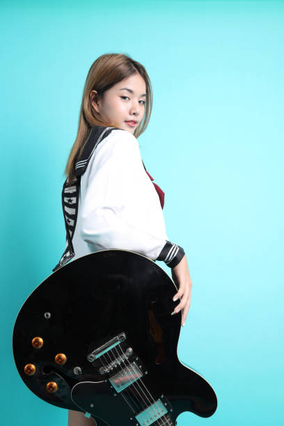 Expressive Caucasian Guitar Player With Yellow Bass Guitar Posing In Fashionable Fur Red Jacket With Shiny Instrument Shouting Over Trendy Pink Background. Vertical Orientation