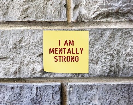 Note stick on rough wall with text I AM MENTALLY STRONG, to remind self to have positive self-esteem to gain ability to take risks, try new things, and cope with life difficult situations